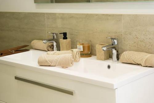 a bathroom sink with two faucets and towels on it at Les Villas de l'Ill in Didenheim