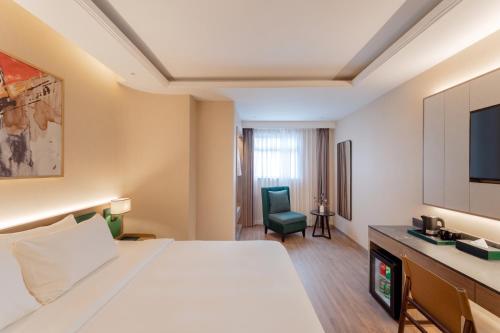 a hotel room with a bed and a tv at NiK Hotel Thi Sach in Ho Chi Minh City