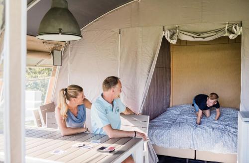 a family sitting on a bed in a bedroom at Camping Begur - Luxe Lodge in Begur