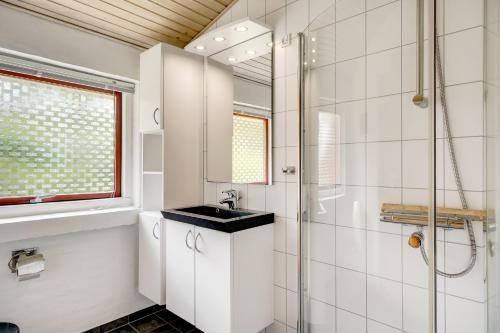 a white bathroom with a sink and a shower at Skovvang 80 in Nørre Nebel