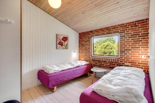 a room with two beds and a brick wall at Skovvang 80 in Nørre Nebel