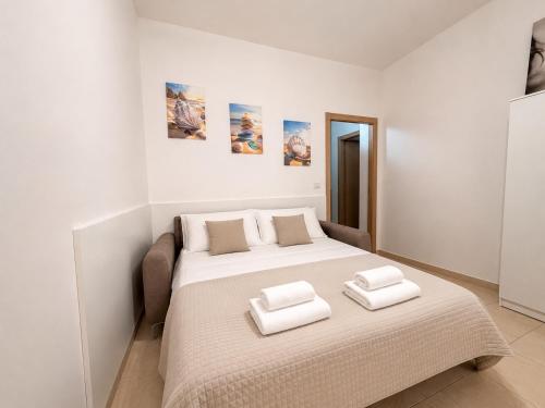 a white bedroom with a bed with two towels on it at Supera Home in Gallipoli