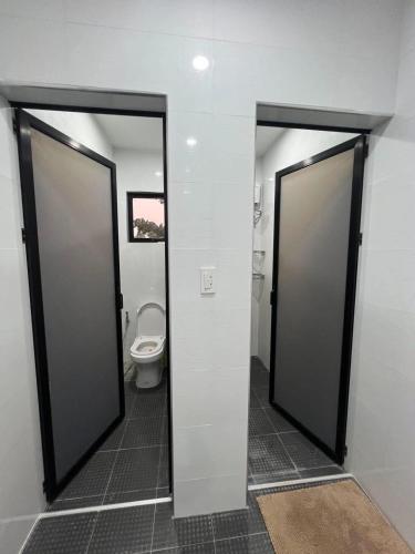 two doors to a bathroom with a toilet in it at Rams home in Moalboal