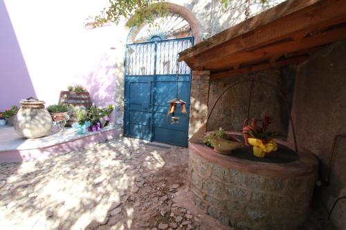 a courtyard with a blue door and a stone fountain at Vesta in Sorgono