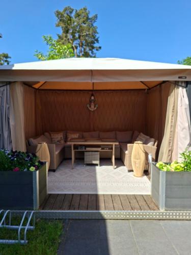 a covered patio with a couch and a table at Comtesse-Camping Plauer See in Brandenburg an der Havel