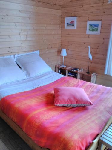 a bedroom with a large bed with a pink pillow at Le Chalet in Ouistreham