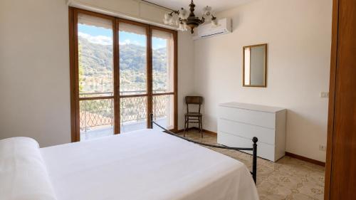 a bedroom with a white bed and a large window at Casa Eliana - Camporosso in Camporosso