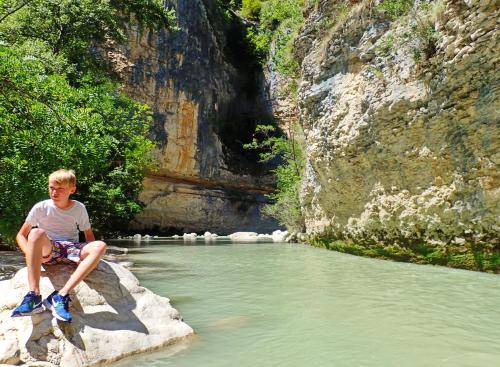 a young boy sitting on a rock by a river at Agriturismo "Borgo Madonna degli Angeli" - charming cottages in the gardens ! in Tocco da Casauria
