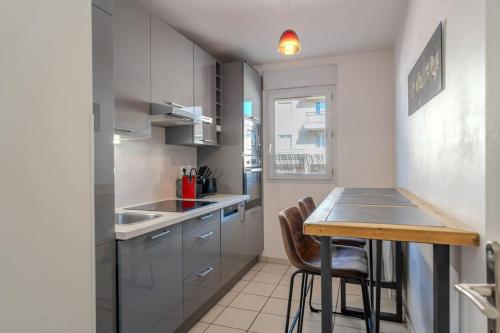 a small kitchen with a wooden table and chairs at Le Jardin de l'Atrium - Appartement moderne proche de Genève et Palexpo in Saint-Julien-en-Genevois