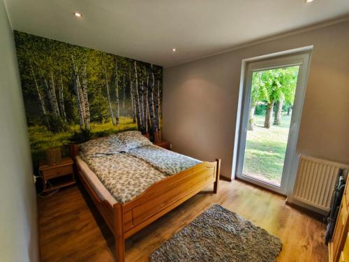 a bedroom with a bed with a painting of trees at Domek Łagów Lubuski in Łagów