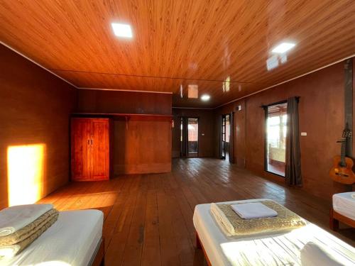 a large room with two beds and a wooden floor at Dico Surf Point- Surf Lodge in Simeulue in Lasikin