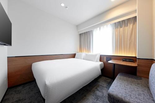 a bedroom with a large white bed and a chair at Sotetsu Grand Fresa Osaka-Namba in Osaka