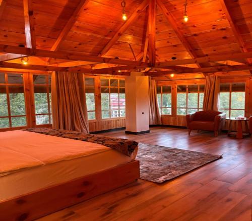 a bedroom with a bed in a room with windows at Fogland Hotel Nathia Gali in Nathia Gali