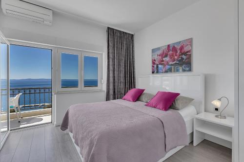 a bedroom with a bed with pink pillows and a balcony at Villa King Apartments in Brela