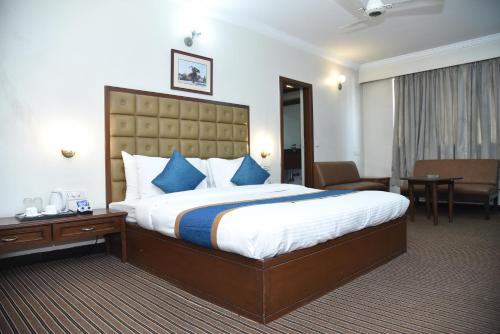 a hotel room with a large bed with blue pillows at Belair Suites in Pune