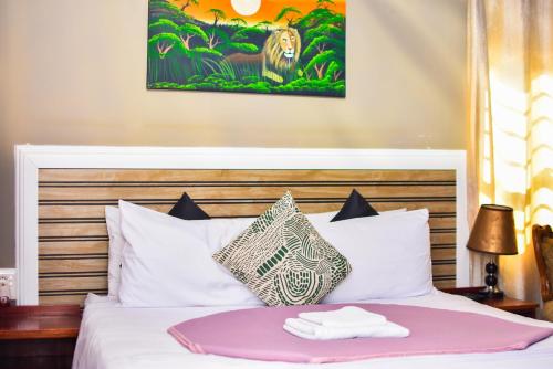 a hotel room with a bed with a monkey painting on the wall at MKHUZE INN in Mkuze