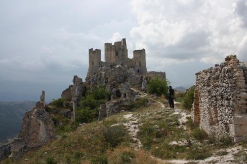 a man standing on a hill with a castle on top at Agriturismo "Borgo Madonna degli Angeli" - charming cottages in the gardens ! in Tocco da Casauria
