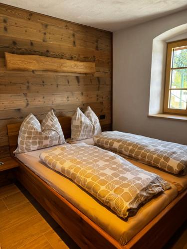 two beds in a bedroom with a wooden wall at Ferienwohnung Almzeit in Gressenberg