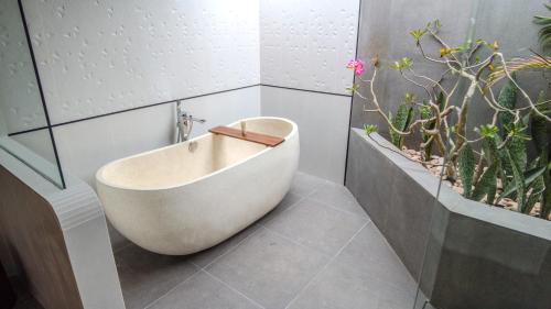 a bath tub in a bathroom with potted plants at Merumatta Senggigi Lombok in Senggigi