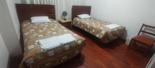 a hotel room with two beds and a chair at LUANAIRAM Home in Cusco