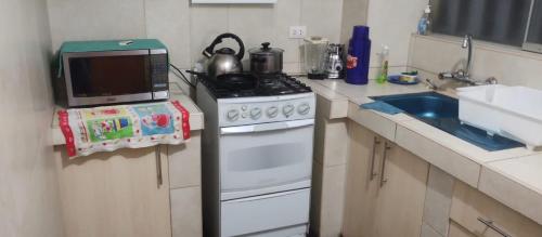 a small kitchen with a stove and a microwave at LUANAIRAM Home in Cusco