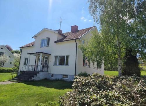 a white house with a tree in the yard at Lägenhet i Sandhem in Sandhem