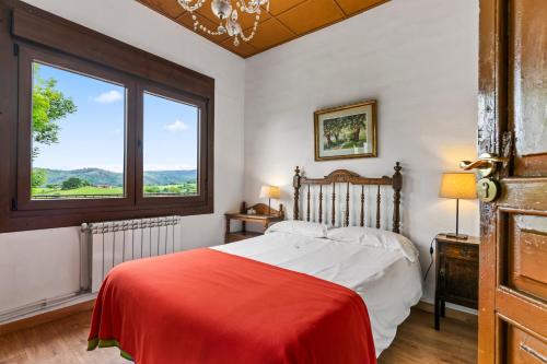 a bedroom with a bed with a red blanket and a window at La casona de La Garaba in Grado
