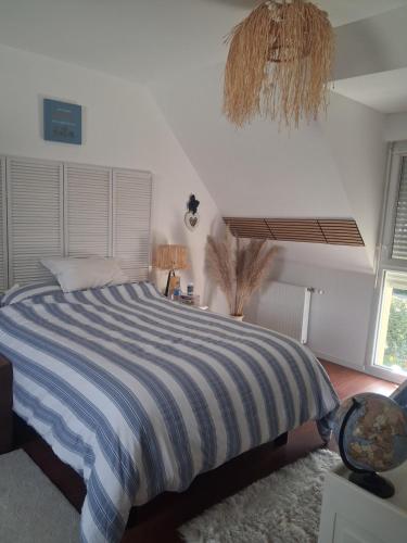 a bedroom with a bed with a blue and white striped comforter at Maison ensoleillée plage a pied in Houlgate