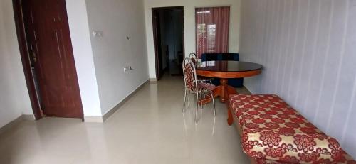 a dining room with a table and chairs and a table and a couch at Roamwander APARTMENT in Vagamon