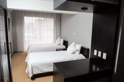 a hotel room with two beds and a window at Suites Parioli in Mexico City