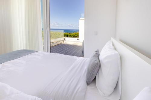 a white bedroom with a view of the ocean at Villa Atlantica One Sea View - Pool - Sunset in Lourinhã