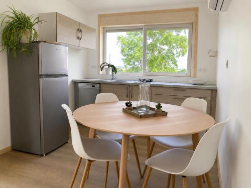 a kitchen with a wooden table and white chairs at Le pré du bonheur in Saint-Georges-sur-Baulche