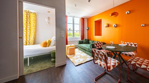 a living room with orange walls and a table and chairs at Pop Hôtel in Dijon