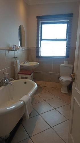 a bathroom with a tub and a toilet and a sink at Pelagus Guest House in Hermanus