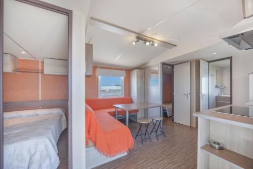a bedroom with an orange bed and a table at Bungalow Tranquilo Cerca de Roche in Conil de la Frontera