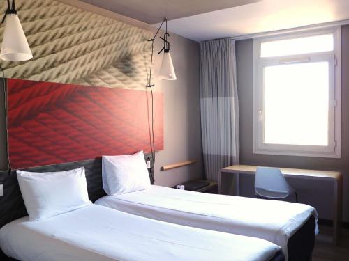 a hotel room with two beds and a window at Ibis Irun in Irún