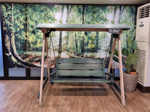 a bench in front of a mural of a forest at The Blossom Yeonnam Guesthouse in Seoul
