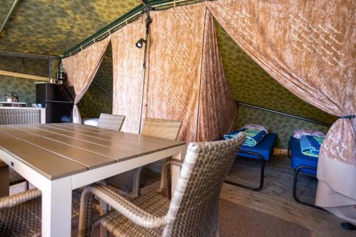 a dining room with a table and chairs in a tent at Duynlodge Ameland direct aan het strand in Nes