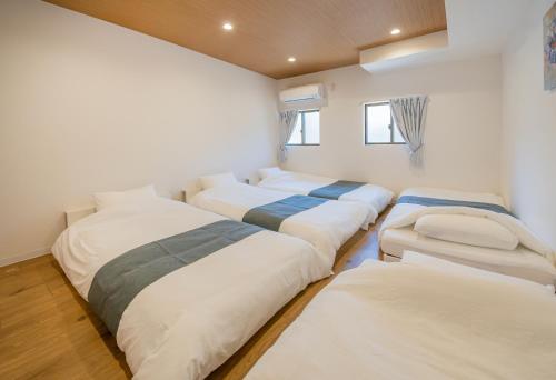 a room with a row of beds in it at HOTEL Itsuki in Onomichi