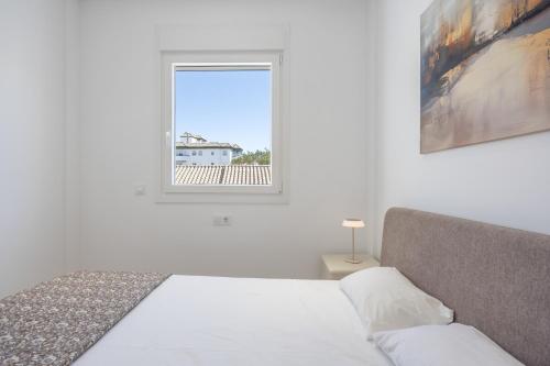 a white bedroom with a bed and a window at Complejo Los Drogos in Novo Sancti Petri
