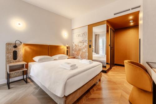 a bedroom with a large white bed and a chair at Art Queen Aparthotel in Krakow