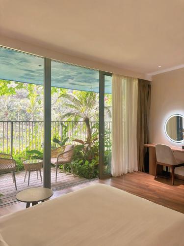 a bedroom with a bed and a large window at Chốn Mộc - Cát Bà Resort in Cat Ba