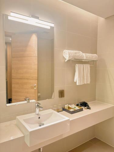 a white bathroom with a sink and a mirror at Chốn Mộc - Cát Bà Resort in Cat Ba
