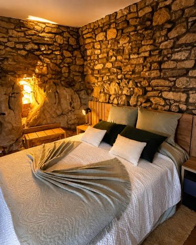 a bedroom with a bed with a stone wall at Suite Pedra Oliveira - Piscine salée privée - Proche Coimbra - Centre Portugal in Ameixeira
