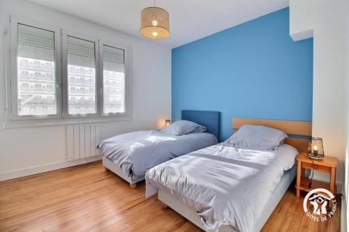 two beds in a room with blue walls and wooden floors at Les sternes in Étel