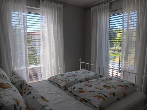 a bedroom with two beds in front of windows at Lagrette Ferienwohnung am Hainer See in Neukieritzsch