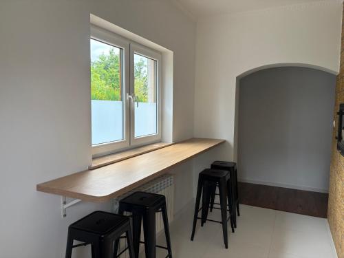 a kitchen with a counter with stools and a window at Pensjonat Perła in Grzybowo