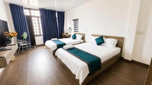 a hotel room with two beds and a television at Mubee Homestay in Hue