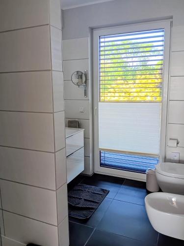 a white bathroom with a toilet and a window at Lagrette Ferienwohnung am Hainer See in Neukieritzsch