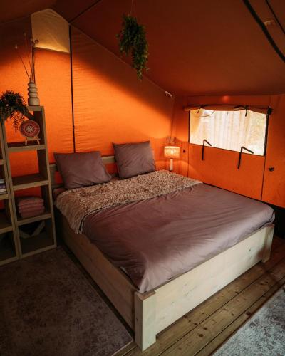 a bed in a room with an orange wall at SoulSafari aan Zee in Julianadorp